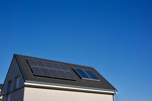 A house with solar panels covering its tiled roof under a clear blue sky on a sunny day