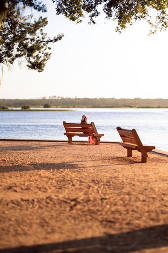 A woman sitting on a wooden bench while looking at a Palm Coast, Florida, USA