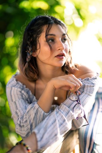 An attractive young woman holding glasses while looking at something