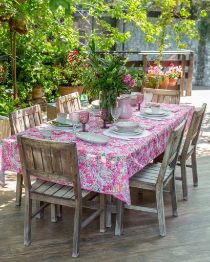 Rural lunch table with empty dish set on colorful tablecloth and bouquet of freshly picked garden flowers