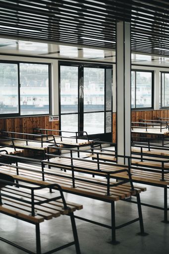 A vertical shot of benches inside a ferry with windows overlooking the sea