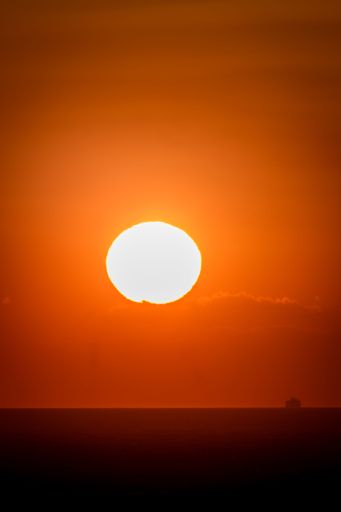 A vertical closeup of orange sun over sea during sunset