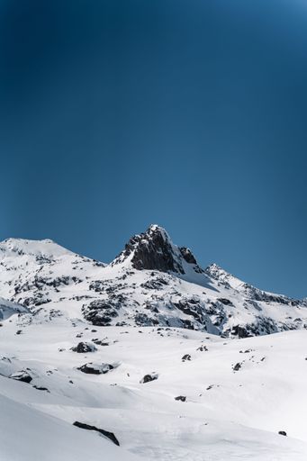 A vertical shot of a beautiful mountain peak covered by snow