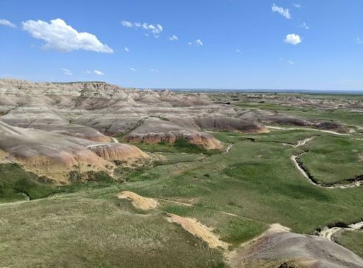 A panoramic shot of a prairie with a fault and clear blue sky in Badlands National Park, South Dakota