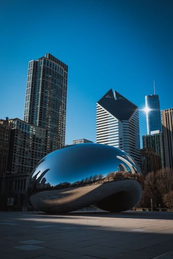 A vertical low angle shot of Chicago Bean with buildings in the background