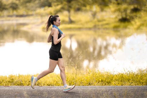A scenic view of an athletic woman jogging by a lake on a beautiful day