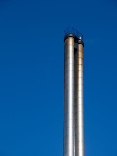 A vertical shot of metal chimney in front of a blue sky