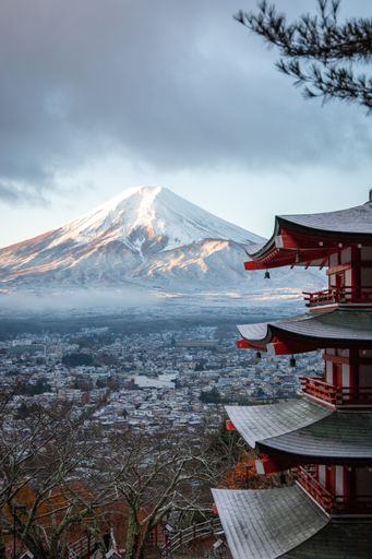 A closeup shot of a historic Pagoda with cityscape and mountains in the background