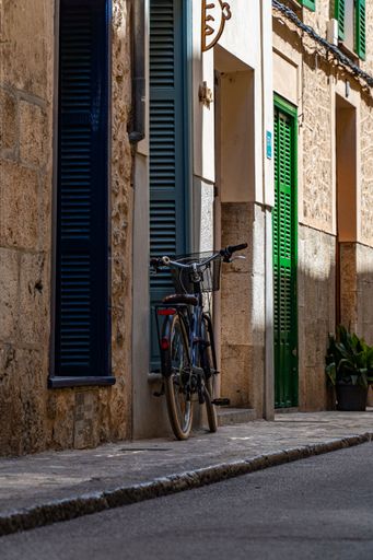 A vertical shot of a bicycle parked on the sidewalk near the building