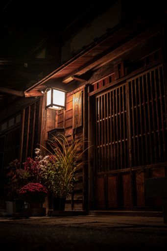 A vertical shot of a house with an illuminated lamp at night time