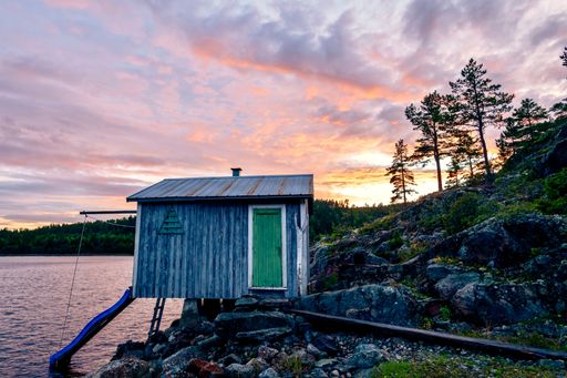 A small wooden cabin on the seashore during a beautiful sunset