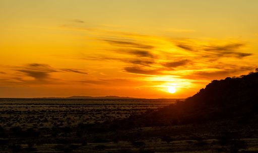 A mesmerizing sunset sky over the desert field in Namibia, Africa, with a silhouette of a hill in the background