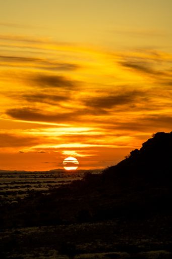 A breathtaking sunset sky over the desert field in Namibia, Africa, with a silhouette of a hill in the background