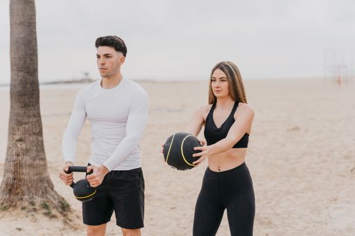 A closeup shot of a Spanish girl and a Spanish man exercising near the beach