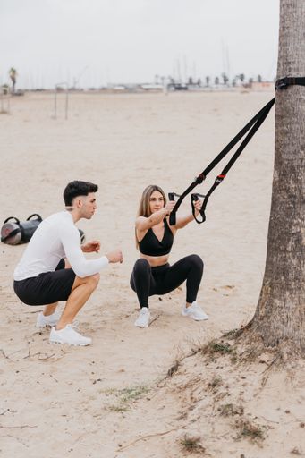 A vertical shot of a Spanish girl and a Spanish man exercising near the beach
