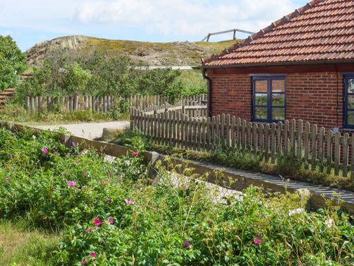 A traditional red brick house in the foreground of a lush green landscape