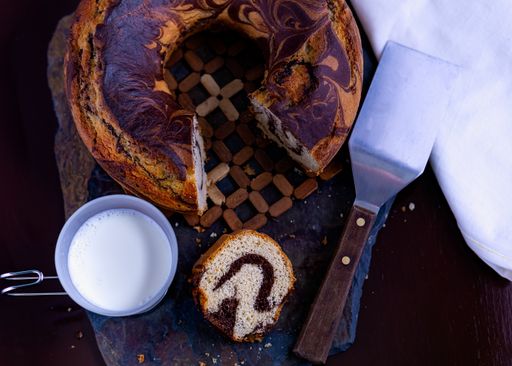 A high angle shot of a delicious homemade marble pound cake and cup of fresh milk on a slate board