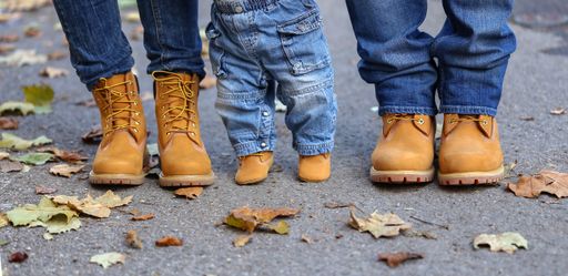 A closeup of the legs of a family of three wearing denim  and yellow boots
