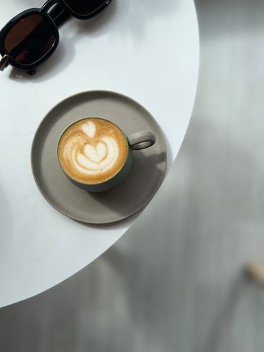 A top shot of a morning coffee on the table with black sunglasses next to it, concept of freshness