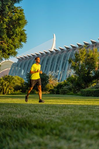 Hispanic handsome man jogging during sunset in the park garden of the city of arts and sciences, Valencia, Spain.