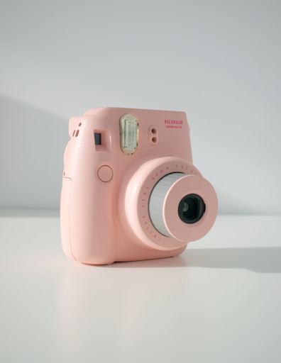 A vertical shot of a pink Fujifilm Polaroid Instax mini8 on a white background