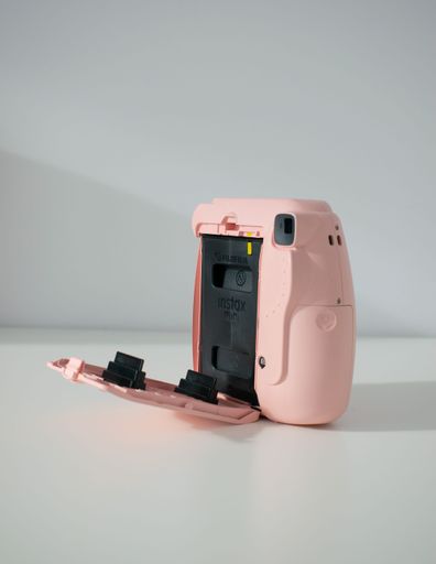 A vertical shot of a pink polaroid camera on the white background