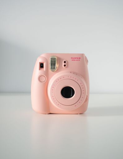 A vertical shot of a pink Instax mini 8 camera on a white background