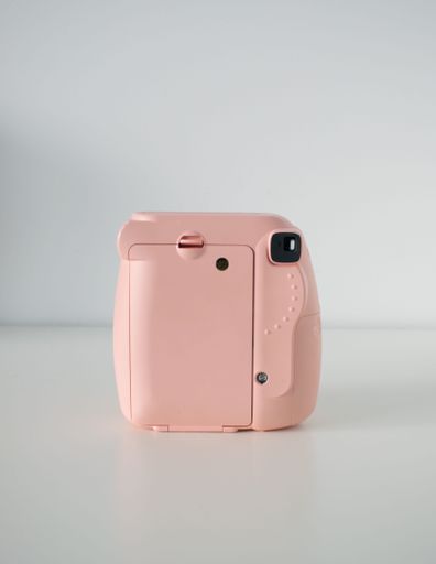 A vertical shot of a pink Instax mini8 camera on a white background