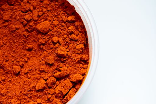 A top view of a ground cayenne pepper in a bowl on a white background