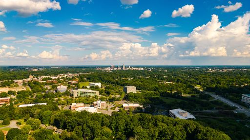 A beautiful aerial view of Greensboro with forests and buildings on a sunny day in Piedmont Triad, NC