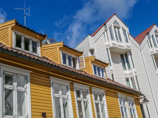 A low-angle view of beautiful suburban houses with white and yellow exteriors seen on a sunny day