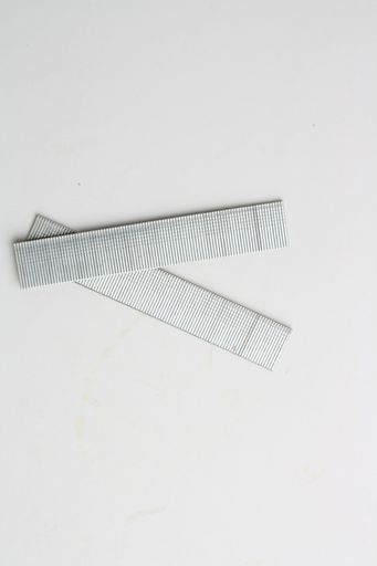 A top view of replacement nails for a nail gun on a gray surface under the lights