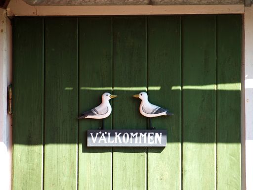 A closeup shot of a wooden door with welcome-sign in Swedish