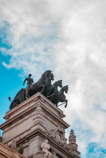A vertical low angle shot of a statue of horses in Madrid, Spain