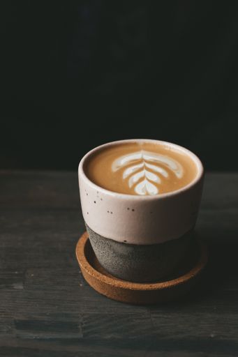 A vertical shot of a ceramic cup of a foamy caffe latte on a wooden table