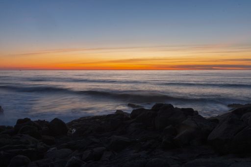 A breathtaking shot of ocean waves calmly moving towards the shore during the beautiful sunset