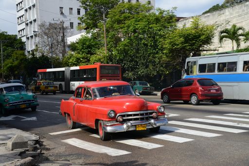 Red American car in Havana dating from 1950s being used as taxi. This is typical of many cars still being driven in Cuba. In background: Soviet Ladas.