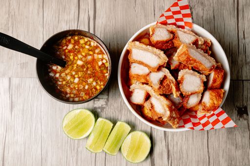 A top view of Lechon kawali pork belly slabs and a bowl of vegetable soup on a wooden table