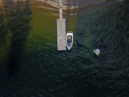 A high angle shot of a boat next to a wooden pier on a lake