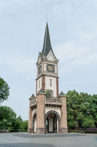 A vertical shot of a clock tower with trees and sky in the background