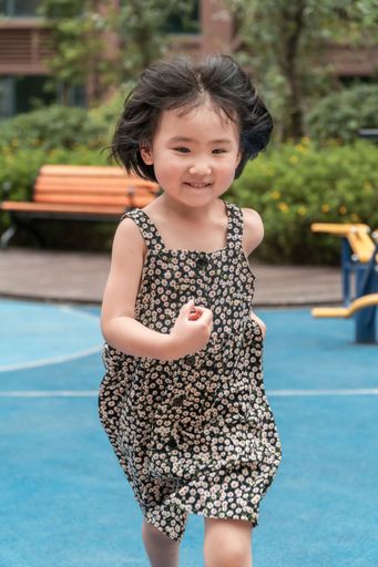 A vertical shot of an East Asian little girl playing in the playground