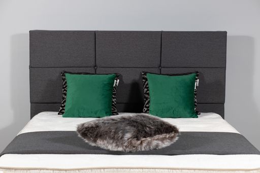 A modern bed with gray upholstery and a fluffy pillow