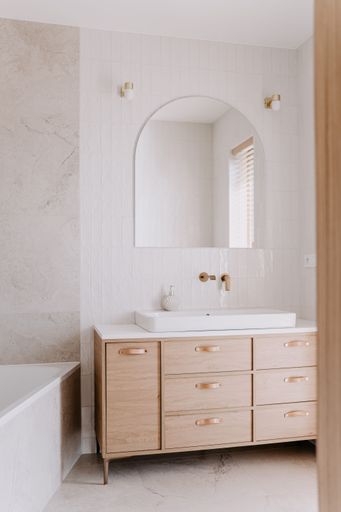 A modern bathroom featuring a white porcelain sink in front of a large mirror