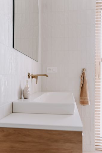 A modern bathroom featuring a white porcelain sink in front of a large mirror