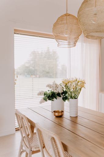 An interior shot of a contemporary styled living space with a wooden table and vases full of flowers