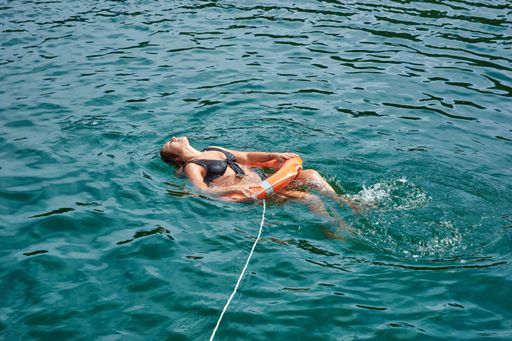 A Hispanic attractive young woman swimming in the water in  a lifebuoy