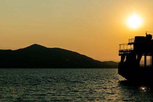 A boat and mountain silhouette on the sea at sunset