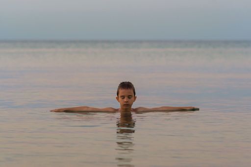 A male meditating and relaxing in the sea at sunset