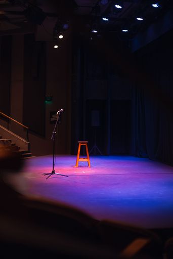 A shallow focus of a microphone on a stage with purple lights