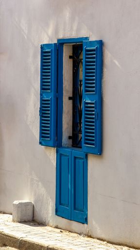 A blue window with louvers with shadows, in Annibale Preca Street, Lija, Malta